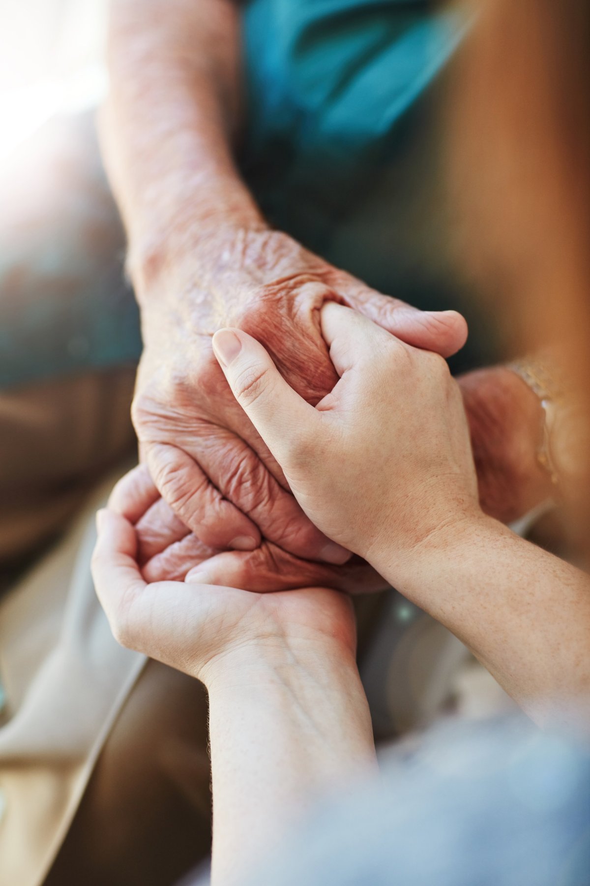 A woman holding a senior man's hands in comfort and compassion